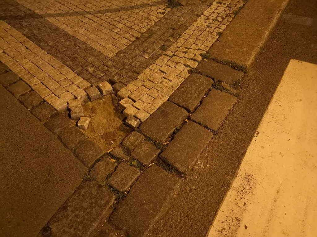 Drolící se dlažba chodníku u přechodu před domem Balbínova 20 (P2)
