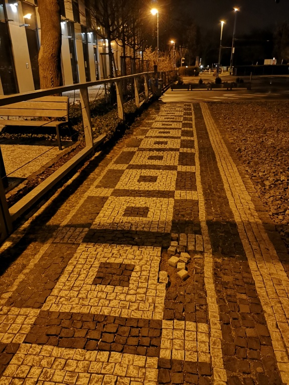 Drolící se dlažba na chodníku vedle budovy České spořitelny