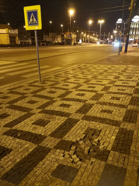 Poškozená dlažba na chodníku u zast. Želivského (P3)