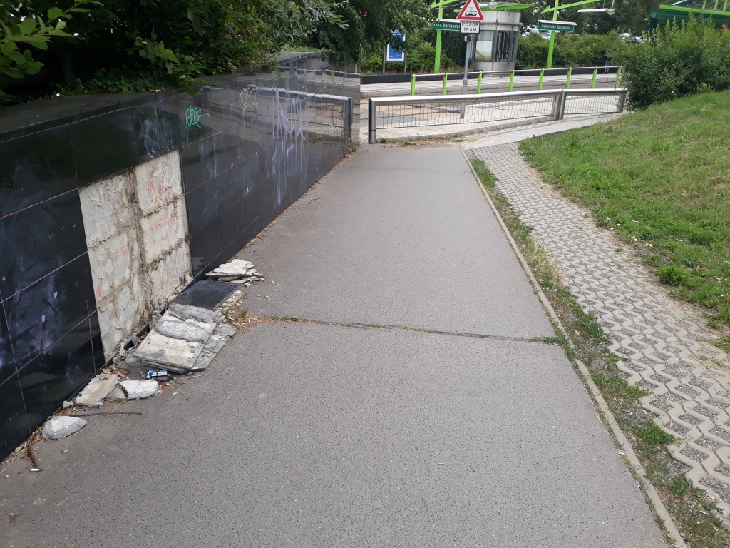 Dlaždice ze zdi padají na chodník - u tramvaje Poliklinika Barrandov
