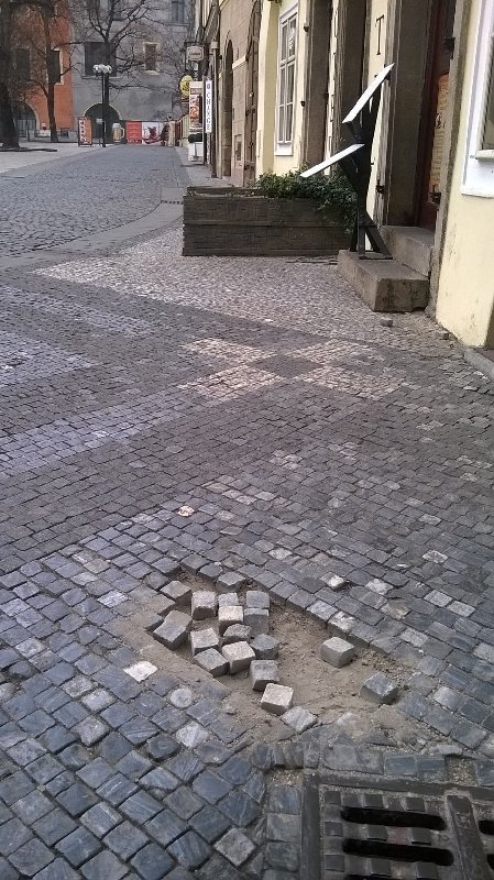 Díra a rozházené kostky okolo v Mikulášské ul.