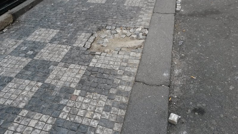 Vypadané dlažební kostky v ulici Malá Štupartská 