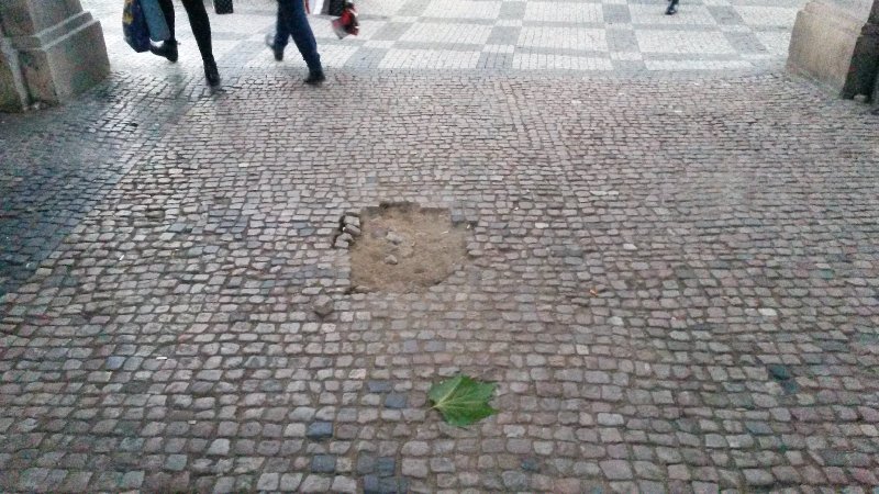 Vypadané dlažební kostky v průchodu vedle tram. zastávky Jindřišská