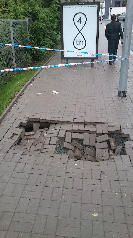 Díra v dlažbě chodníku po povodni