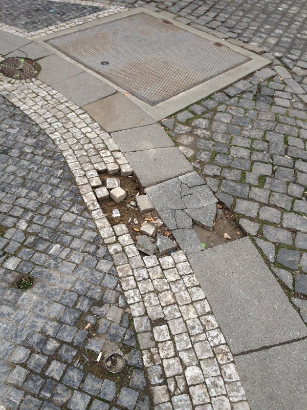 Rozpadající se dlažba na rohu Havelské a Železné
