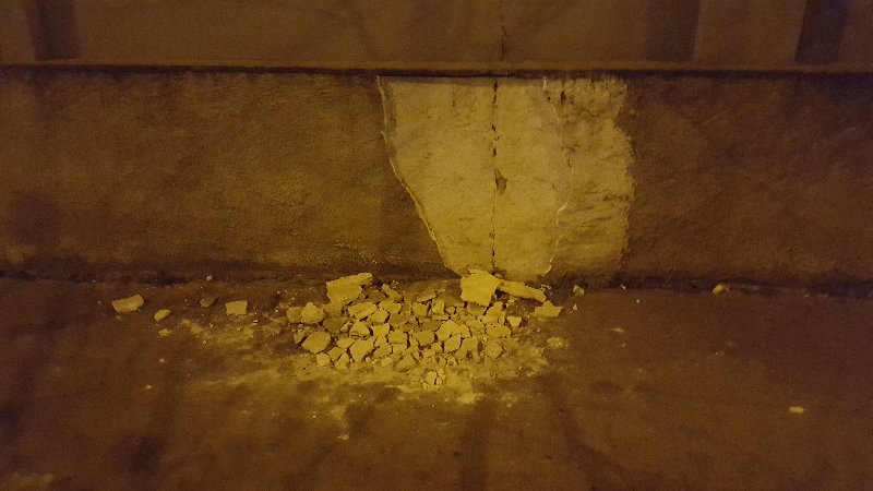 Odpadlá omítka v ulici Jana Želivského u zastávky Mezi hřbitovy