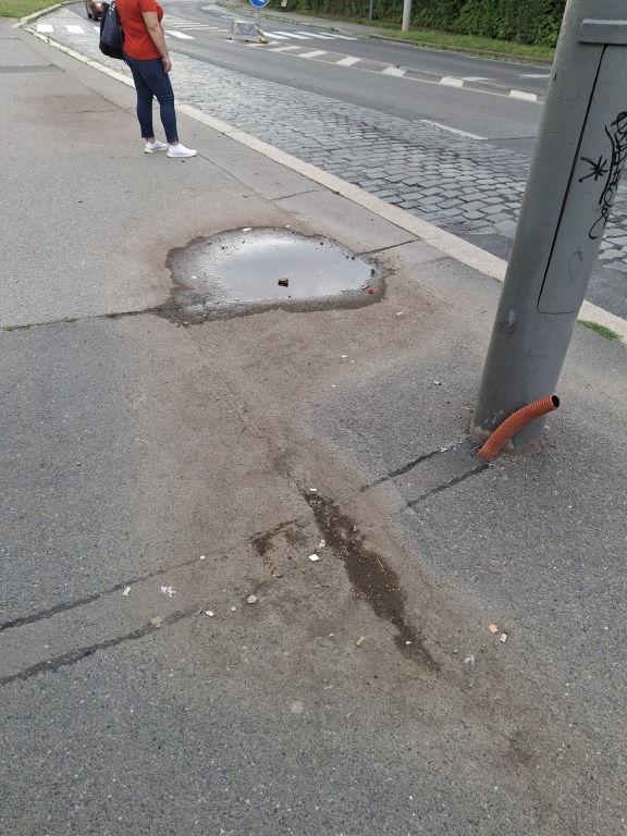 Kaluže na nástupišti autobusové zastávky Pavelkova