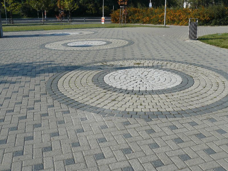 Chodník přes parkoviště za nákupním centrem u metra Prosek