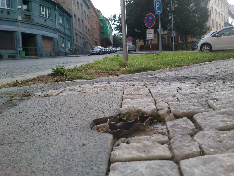 Z chodníku trčí ostrý pozůstatek tyče