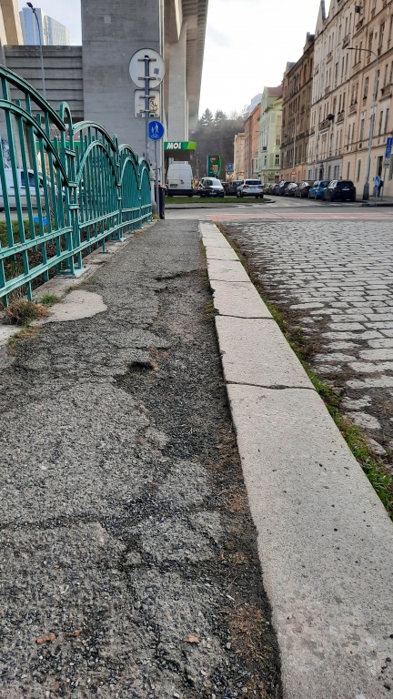 Díra v asfaltu na chodníku mostu