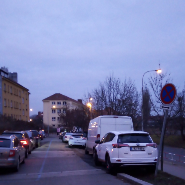 Auta parkující na chodníku U Družstev a na svahu v ulici Sdružení